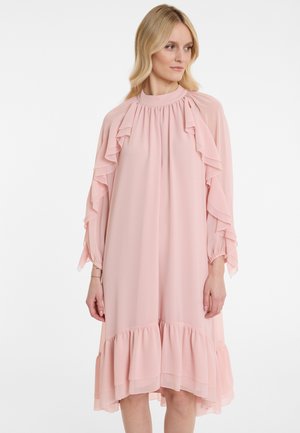 Helles rosa Kleid aus fließendem Stoff, mit Rüschendetails an den Ärmeln und dem Saum, in lockerer Passform und mit hohem Kragen.