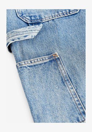 Sininen farkkukangas, jossa on hienovarainen textura, etutasku ja tavanomainen ompelu. Suunnittelu on rento ja toiminnallinen.