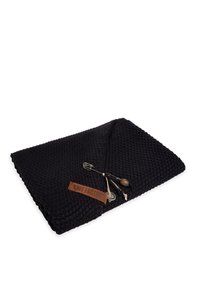 Zwarte, gestructureerde deken met een geweven patroon. Inclusief een leren label met de tekst "Knit Factory" en decoratieve hardware accenten.