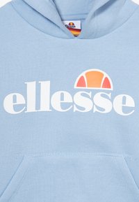 Sweat à capuche bleu clair avec un logo blanc "ellesse" et un graphique en demi-cercle avec des accents orange et jaune. Comprend une poche avant.