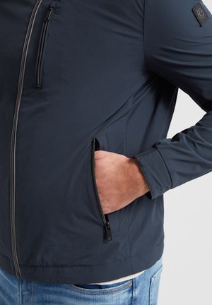 Navy lightweight jacket with a smooth texture, zippered chest pocket, and side hand pocket. Features elastic cuffs and detailed stitching.