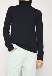Czarny sweter z golfem z długimi rękawami, wykonany z miękkiego dzianinowego materiału. Posiada dopasowany krój oraz ściągacze przy mankietach i dole.