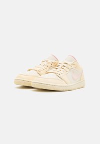 Sneakers beige chiaro con tomaia in pelle liscia, dettagli rosa, punta traforata e linguetta testurizzata. Suola in gomma per una buona trazione.