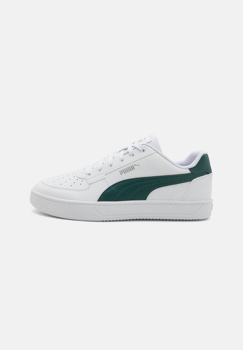 Hvide sneakers med en glat læderoverdel, grøn accent på siden, perforeret tå, flade hvide snørebånd og struktureret gummisål.