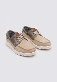Zapatos casuales de ante en tonos marrón y beige con suelas de goma blanca, que cuentan con cordones redondos y un acento de cuero en la lengüeta.
