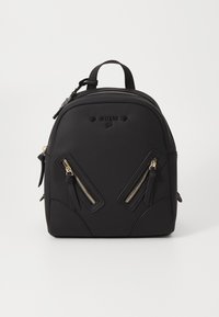 Sac à dos noir avec une texture lisse, doté de deux zips frontaux inclinés avec des accents dorés et d'une poignée supérieure. Logo de la marque embossé à l'avant.