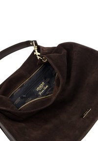 Bruine suède handtas met een enkele schouderband, gouden hardware en een ritsvak aan de binnenkant. Voering van zwart stof met een logo patroon.