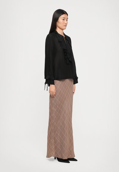 Black blouse with ruffled collar and cuffs, paired with a long brown checkered skirt. Worn with black pointed heels.
