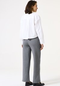 Witte cropped button-up blouse met lange mouwen, gecombineerd met grijze ribbelachtige wijde broek, voorzien van een elastische tailleband en rechte zoom.