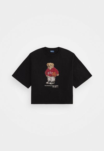 Črna kratka majica iz bombaža, z izvezenim medvedom v rdeči kapuci z napisom "U.S." in košarko, ter besedilom spodaj.