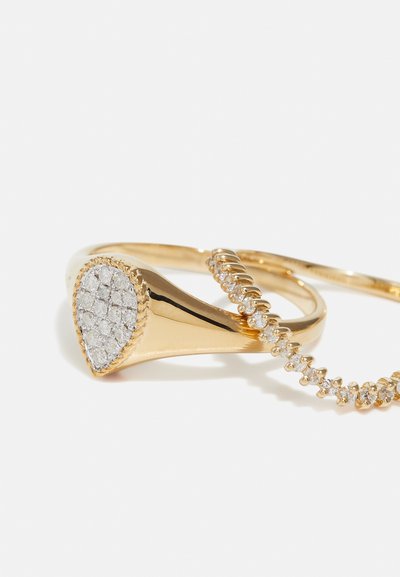 Gold-tone ring set featuring a teardrop-shaped accent with clear gemstones and a delicate band embellished with smaller stones.