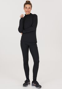 Black athletic long-sleeve top with a half-zip collar, paired with black fitted leggings. Both made from stretchy, moisture-wicking fabric.