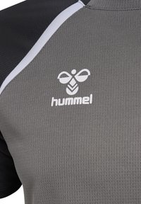 Približek sive in črne športne majice z belim logotipom Hummel in napisom na prsih.