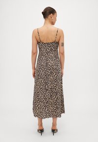 Robe midi à imprimé léopard avec des fines bretelles réglables, une silhouette fluide et un tissu léger, présentant un design épuré et minimaliste.