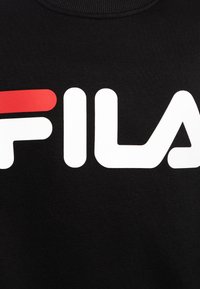 Primer plano de una tela negra con el logo de FILA en letras blancas y rojas.