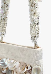 Sac en tissu avec des embellissements en coquillage naturel, couleurs blanche et beige, surface texturée, poignées métalliques torsadées avec des perles décoratives.