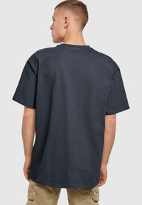 Donkergrijze oversized t-shirt met een geribbelde textuur, korte mouwen en een ronde hals, gezien vanaf de achterkant, met een rechte afgewerkte onderrand.