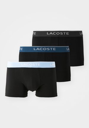 Boxers noirs avec ceintures élastiques ; un avec des accents gris, un avec des accents bleus et un avec des accents bleu clair arborant le logo Lacoste.