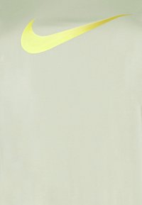 Vaaleanvihreä T-paita, jossa on suuri keltainen Nike Swoosh -logo. Sileä kangas, rento istuvuus ja ilman lisäkuvioita tai grafiikoita.