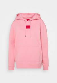 Sweat à capuche rose en tissu doux avec une grande poche avant, une capuche à cordon et un patch logo rectangulaire rouge avec du texte blanc.