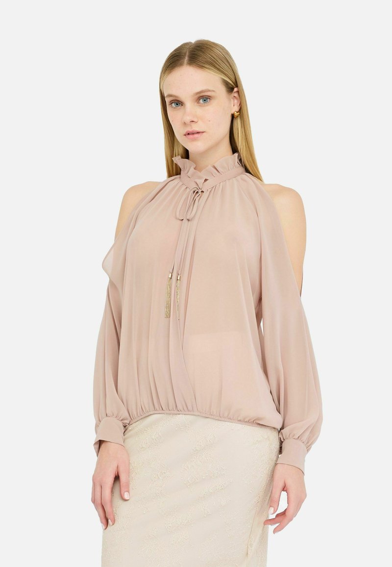 Hele roosa blouse, mis on valmistatud läbi paistvast kangast, rohelise kaelusega, avatud õlgadega ja kogutud allääriga pikal varrukal. Kullarikkad detailid.