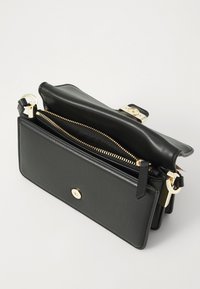 Svart lærveske med gullglidelås og metallbeslag. Har ett hovedrom, en liten clasp og teksturert fôr inni.