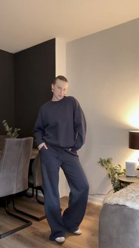 Sudadera oversize azul marino oscuro y pantalones anchos a juego. La tela parece suave y cómoda, con una silueta relajada. Detalles de diseño simples.