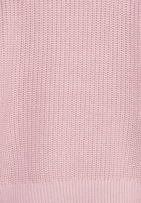 Jasnoróżowy sweter z dzianiny z fakturowanym splotem i ściągaczem u dołu. Materiał wydaje się miękki i elastyczny, o swobodnym kroju.
