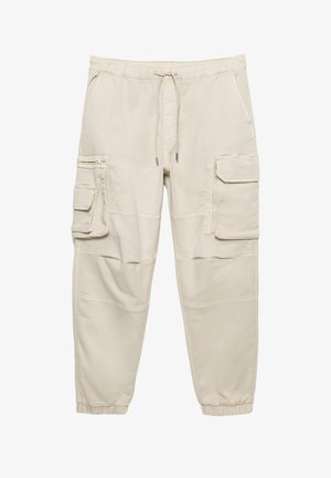 Beżowe spodnie typu cargo z elastycznym pasem ze sznurkiem, dwoma bocznymi kieszeniami oraz dwoma dużymi przednimi kieszeniami cargo. Posiadają elastyczne mankiety i ozdobne przeszycia.