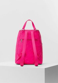 Sac  à dos rose vif avec motifs en relief, bretelles ajustables, poignée supérieure et poche zippée horizontale sur le panneau arrière.