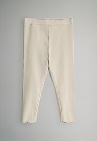 Leggings de canalé en beige claro con una cinturilla elástica y dobladillo con ondas. La tela parece suave y texturizada con líneas verticales.