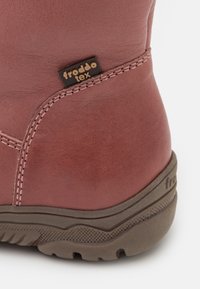 Detailní záběr hnědé kožené boty s podpůrnou stehenní částí, texturovanou tmavou podrážkou a malou značkovou nálepkou "froddo tex".