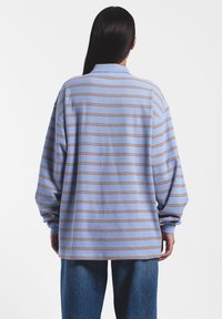 Lichtblauw shirt met lange mouwen en horizontale bruine strepen, relaxed fit en geribde kraag. Gestructureerd breimateriaal.