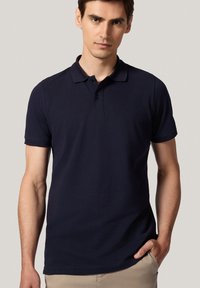 Granatowa koszulka polo wykonana z bawełny, z klasycznym kołnierzykiem, trzema guzikami i krótkimi rękawami. Gładka faktura i dopasowany krój.