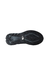 Suola di scarpa nera in gomma con scanalature profonde per una migliore aderenza, caratterizzata da una superficie texturizzata e un logo inciso vicino al centro.