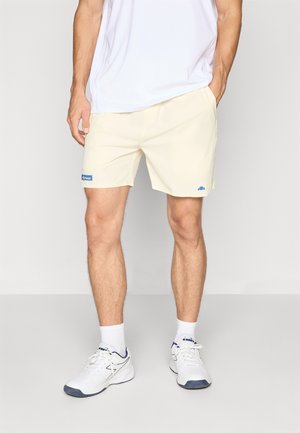 Light yellow shorts made from soft fabric, featuring an elastic waistband, side pockets, and a blue logo patch on the left leg.