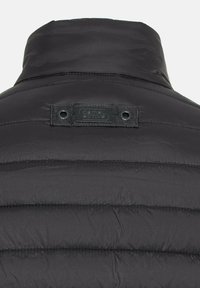 Schwarze Pufferjacke mit vertikalen Nähten, hohem Kragen und einem schwarzen Etikett mit der Marke "Camel Active". Zwei Druckknöpfe am Kragen.