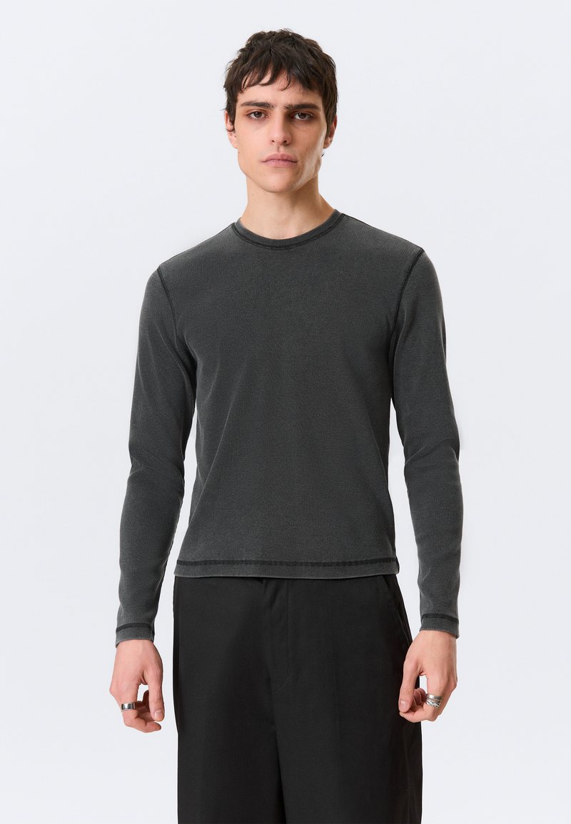 Μακρυμάνικη, σκούρα γκρι ριμπ μπλούζα με στρογγυλή λαιμόκοψη. Διαθέτει άνετη γραμμή και ραφές λεπτομερειών στο τελείωμα και στις μανσέτες.