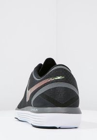 Black athletic shoe with a textured mesh upper, reflective accents, a cushioned sole, and a gray and rose gold swoosh logo.
