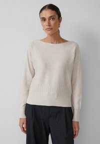 Lichtbeige gebreide trui met een ruime halslijn en geribbelde onderkant. Lange mouwen en een iets losse pasvorm. Gelaagd stof met subtiele details.