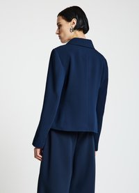 Marineblauer, maßgeschneiderter Blazer mit strukturiertem Kragen, glatter Textur und langen Ärmeln, mit geradem Schnitt und minimalistischem Design.