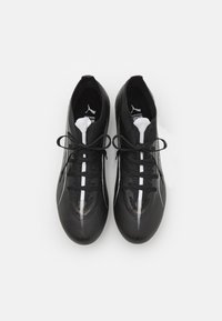 Pantofi sport negri cu o suprafață texturată, accente albe și vârf rotunjit. Caracteristicile includ șirete negre și un logo de marcă pe limbă.