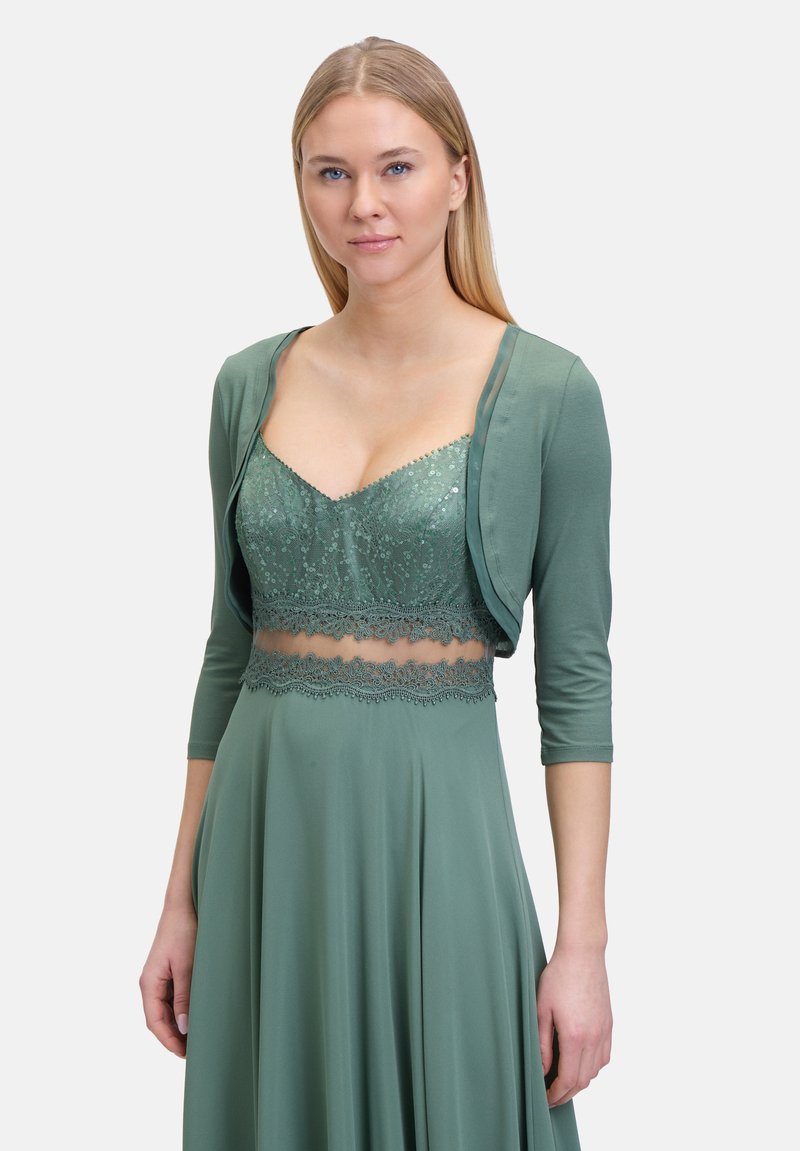 Zielony zestaw sukienki z koronkowym gorsetem, przezroczystą nakładką i rękawami o długości trzech ćwierć. Wykonana z miękkiego, płynącego materiału.