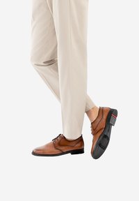 Chaussures habillées en cuir marron avec une finition lisse, au design à lacets, avec un bout légèrement pointu et une semelle en caoutchouc présentant un motif texturé.