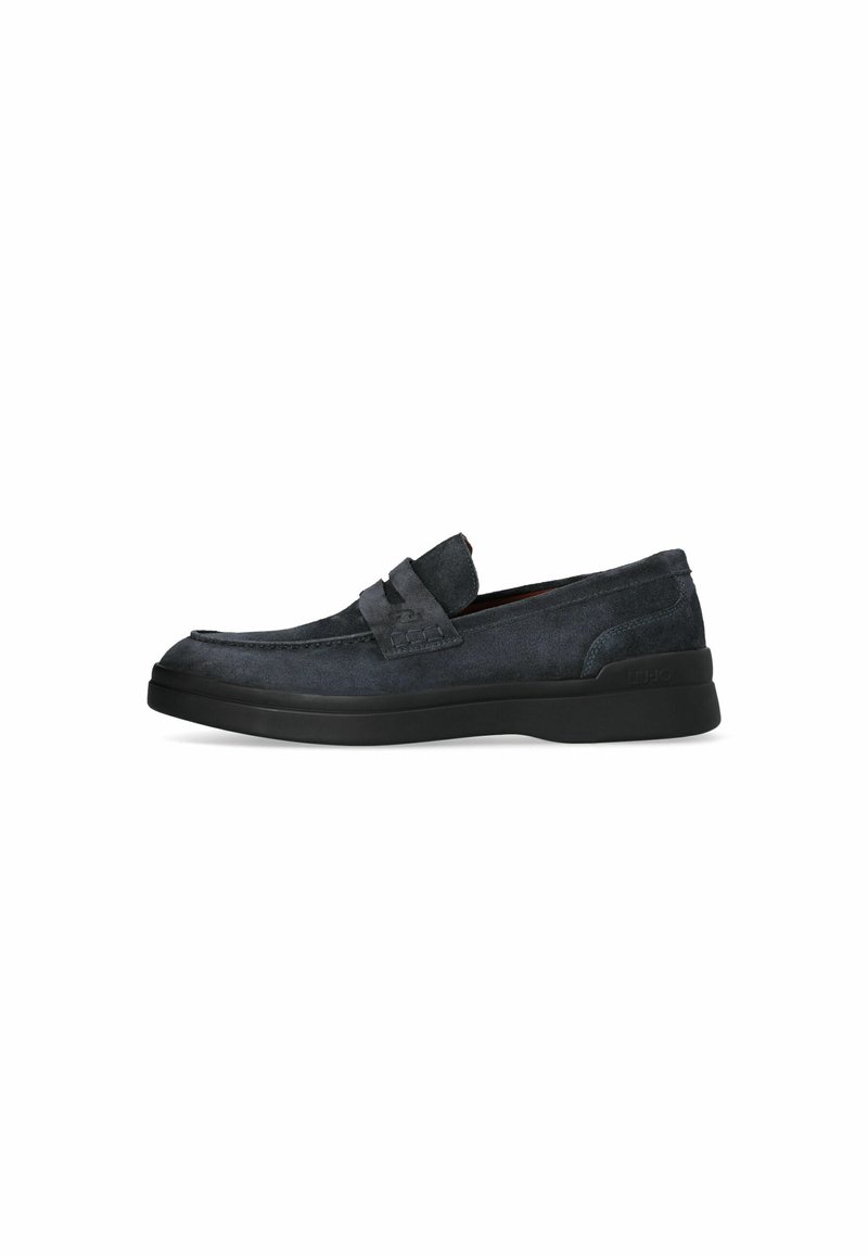 Zapatos azul oscuro de ante tipo slip-on con punta redondeada, costura elevada y suela de goma negra. Presentan una correa decorativa en la parte superior.