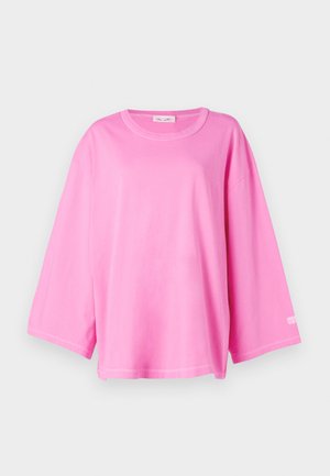 T-shirt en coton rose avec une coupe décontractée, un col rond et des manches à épaule tombante. Présente un texte minimal en blanc en bas à droite.