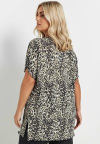 Blusa de estampado de leopardo con mangas cortas, corte holgado y dobladillo ondulado. La tela tiene una textura suave y un diseño ligero y aireado.