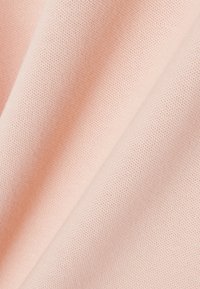 Vaaleanpunainen kangas, jossa on teksturoitu, hengittävä kudonta, hienovaraisilla kuoseilla ja sileällä laskeutumisella. Sopii vaatteisiin tai kodintekstiileihin.