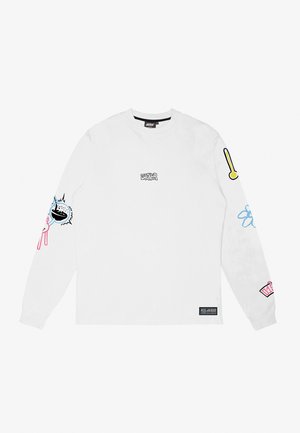 T-shirt blanc à manches longues avec des motifs imprimés sur les manches, présentant des graphiques colorés : une chauve-souris, un chapeau et des formes abstraites. Étiquette affichée en bas.