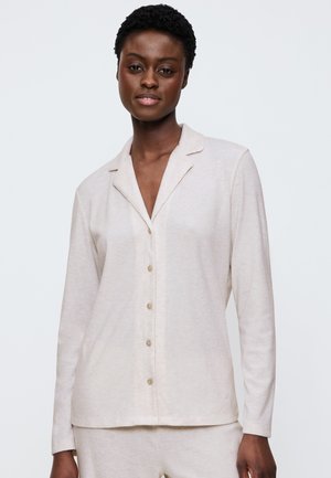 Camicia con bottoni, maniche lunghe, in morbido tessuto beige chiaro con una texture a coste. Presenta un colletto a punta e cinque bottoni sulla parte anteriore.